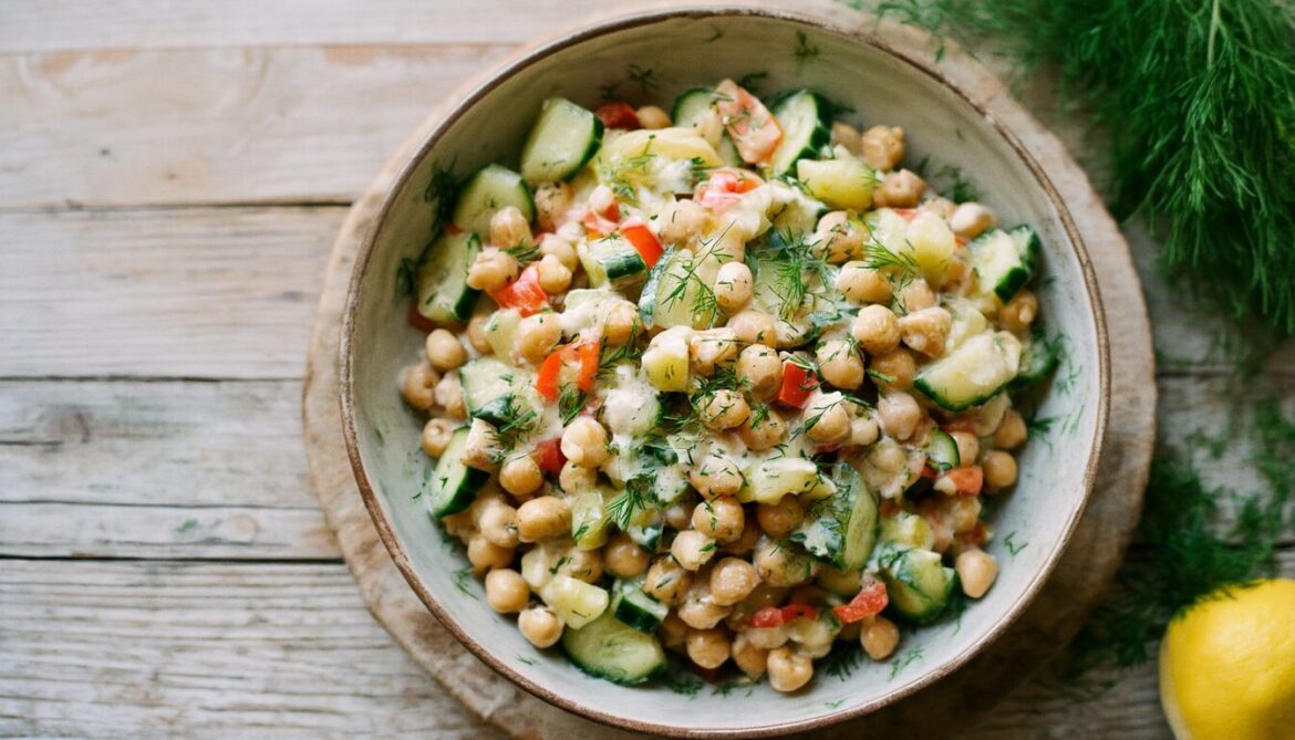 Nudelsalat mit Kichererbsen, Gurke, Paprika und frischem Dill in heller Schüssel mit Joghurtdressing