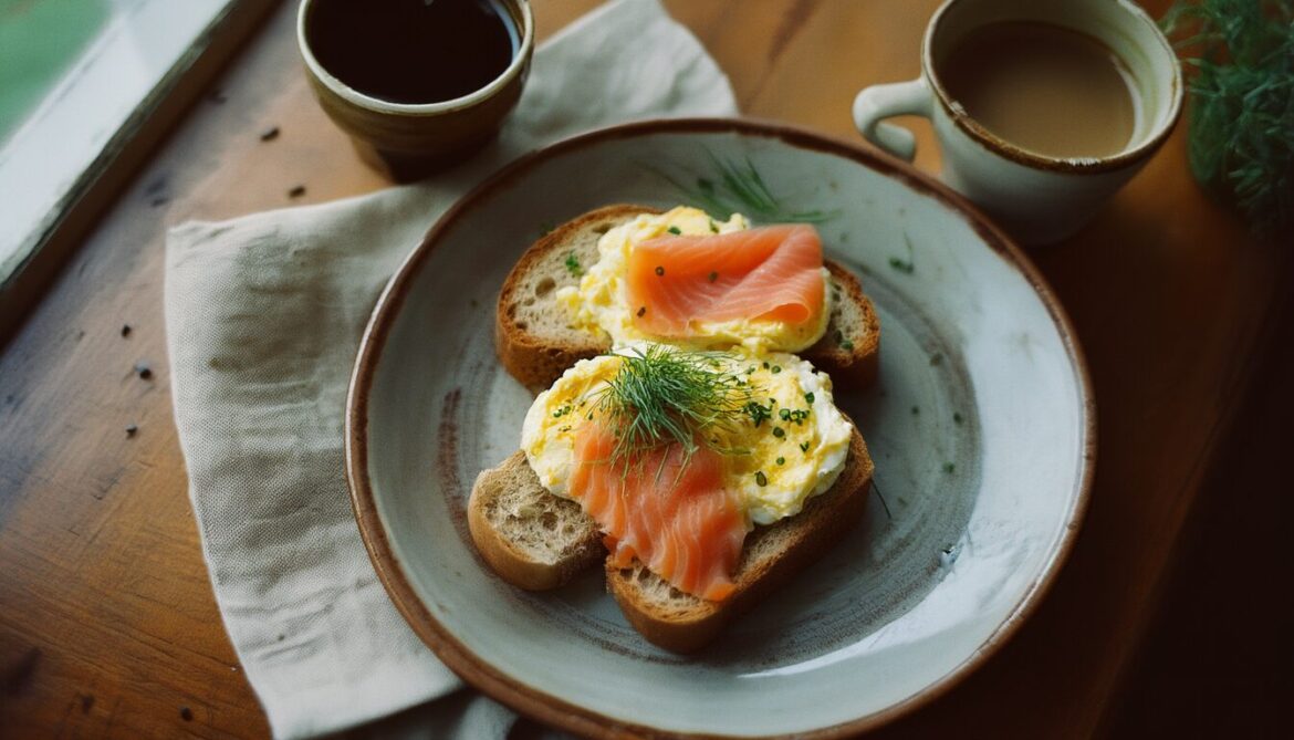 Roggenbrot mit cremigem Rührei und geräuchertem Lachs, garniert mit Schnittlauch und Dill, auf einem rustikalen Teller