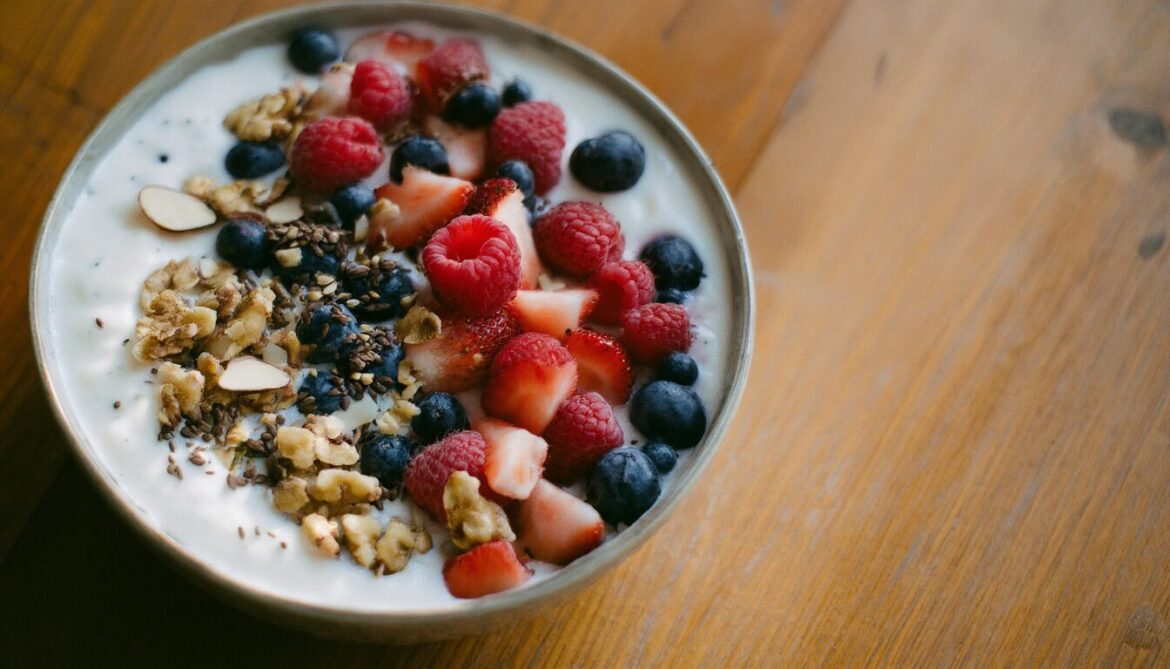 Cremige Skyr-Bowl mit frischen Beeren, gehackten Nüssen und Leinsamen in heller Schale